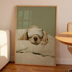 Minimalist oil painting print of a white cocker spaniel tucked up in bed wearing a silk eye mask, painted in soft cream tones against a sage green background