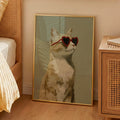 Minimalist oil painting print of a ginger cat in side profile wearing oversized red heart shaped sunglasses, framed in gold, leaning against a bedroom cabinet in a warm styled interior