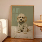 Minimalist oil painting print of a cockapoo sitting on white bedding wearing silk pyjamas, painted in warm cream tones against a soft sage green background