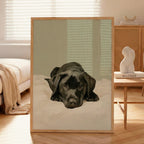 A contemporary oil-style art print of a black Labrador puppy lying on white bedding with a sleepy expression, painted in warm tones against a soft sage green background.